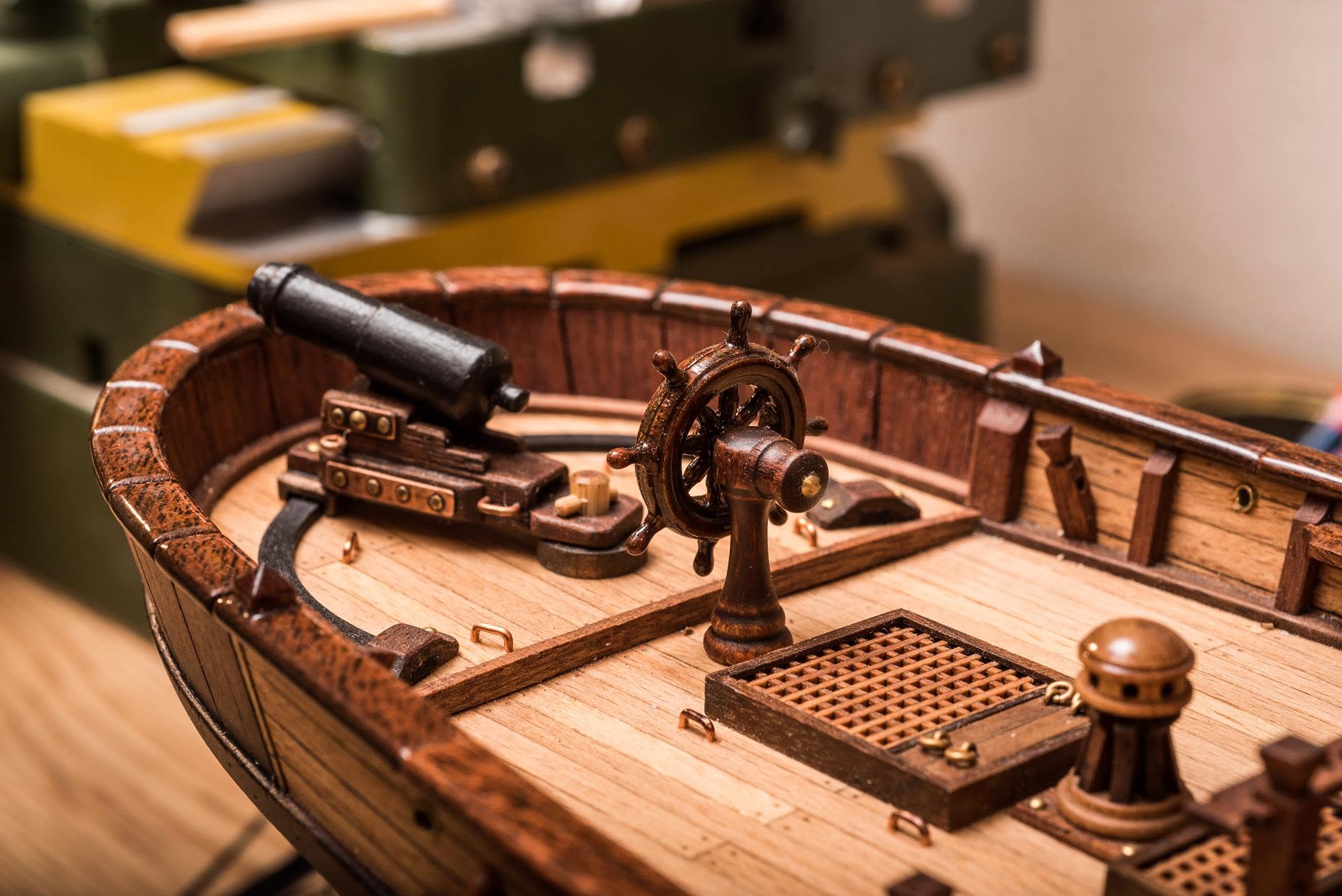 Ship's wheel and a deck cannon on a part-built model, with the workshop behind
